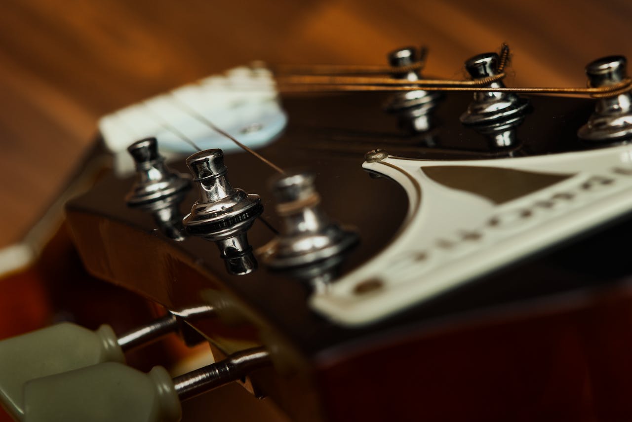 services-04 Extreme close-up of a guitar headstock, focusing on the strings and tuners.