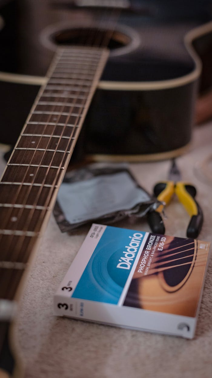 hero-img Acoustic guitar close-up with DAddario strings and guitar tools on a table.