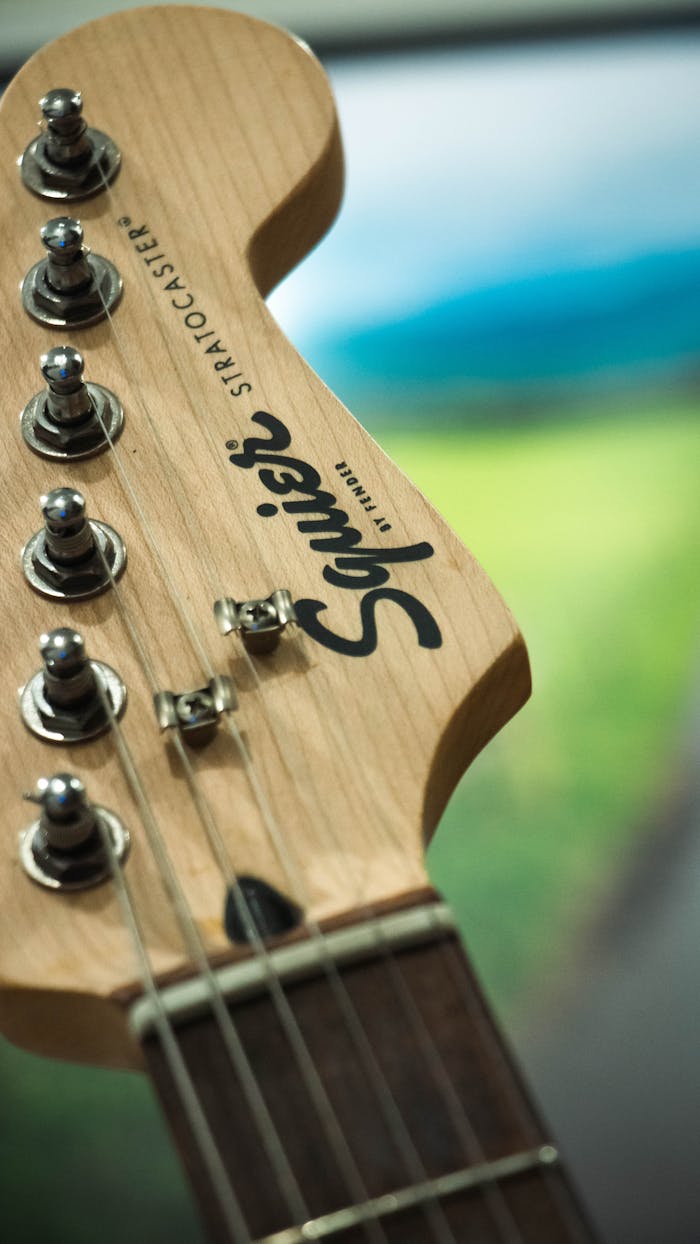 services-01 Detailed view of a Squier Stratocaster headstock with tuning pegs.